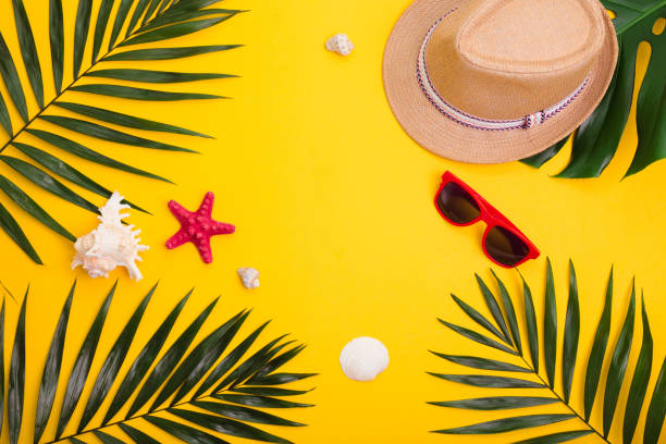istock Hat,tropical palm leaves, sunglasses, sea shells on yellow background. 1152869789