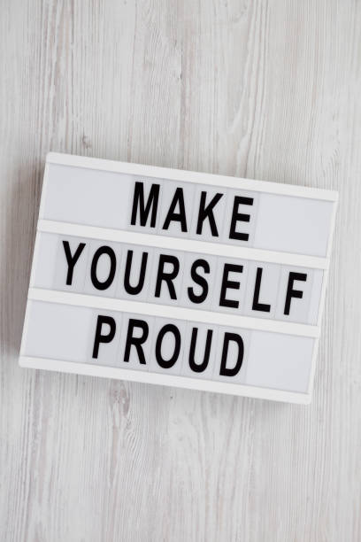 istock Modern board with text 'Make yourself proud' on a white wooden surface, top view. Flat lay, overhead, from above. 1152870468