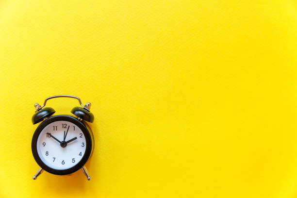 istock Vintage alarm clock Isolated on yellow background 1152871314
