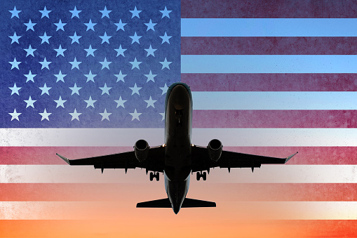airplane on sunset sky with American flag - USA travel concept