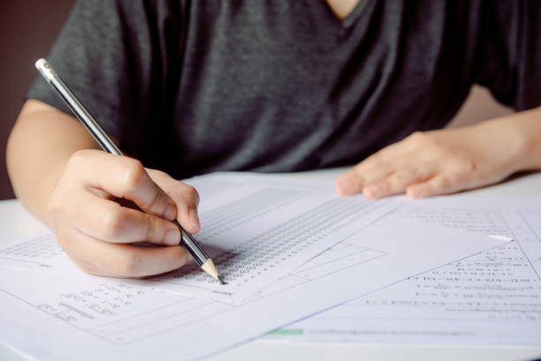 istock Students hand holding pencil writing selected choice on answer sheets and Mathematics question sheets. students testing doing examination. school exam 1152875846