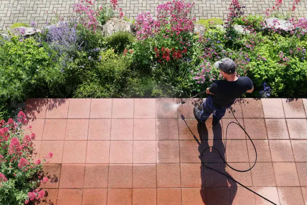 Worker cleaning stone slabs with the high-pressure cleaner, seen from above, with space for text.