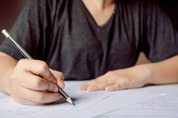 istock Students hand holding pencil writing selected choice on answer sheets and Mathematics question sheets. students testing doing examination. school exam 1152875951