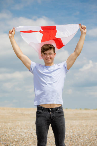 kaukaski mężczyzna na plaży trzymającej angielską flagę - english flag st george flag flying zdjęcia i obrazy z banku zdjęć