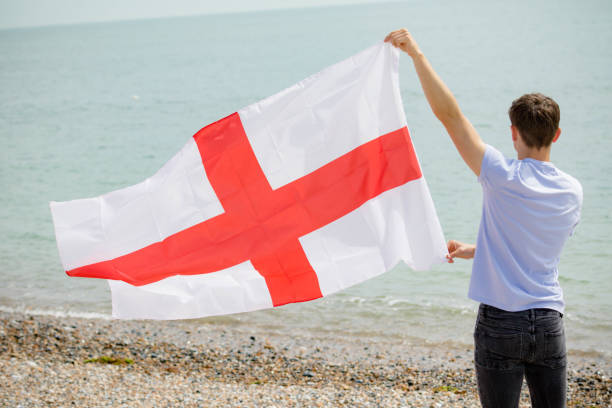 kaukaski mężczyzna na plaży trzymającej angielską flagę - english flag st george flag flying zdjęcia i obrazy z banku zdjęć