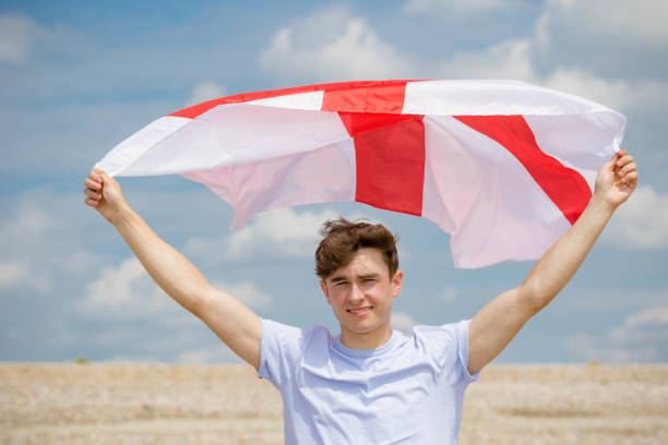 kaukaski mężczyzna na plaży trzymającej angielską flagę - english flag st george flag flying zdjęcia i obrazy z banku zdjęć