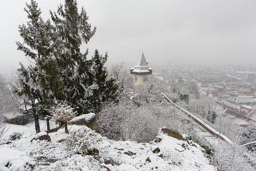 Schlossberg tower and Graz city at snowfall in Austria.