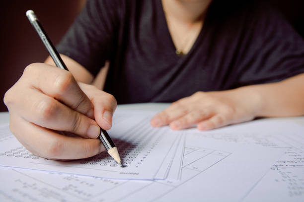istock Students hand holding pencil writing selected choice on answer sheets and Mathematics question sheets. students testing doing examination. school exam 1152876736