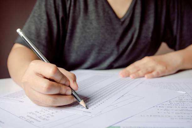istock Students hand holding pencil writing selected choice on answer sheets and Mathematics question sheets. students testing doing examination. school exam 1152876810