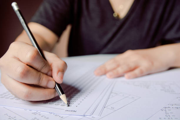 istock Students hand holding pencil writing selected choice on answer sheets and Mathematics question sheets. students testing doing examination. school exam 1152877106