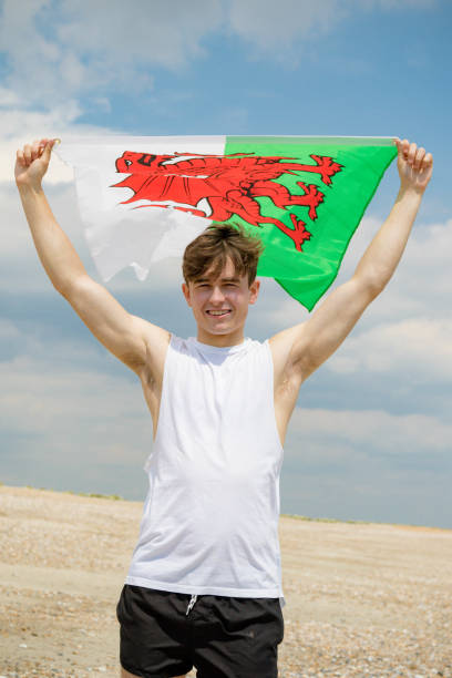 hombre caucásico en una playa sosteniendo una bandera galesa - welsh flag flag welsh culture all european flags fotografías e imágenes de stock