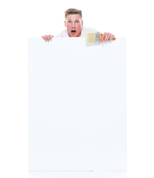 istock Very good looking young white painter standing next to a big white card - shocked 1152880251
