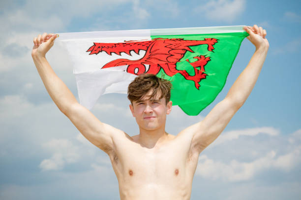 caucasian male on a beach holding a welsh flag - welsh culture wales welsh flag dragon imagens e fotografias de stock