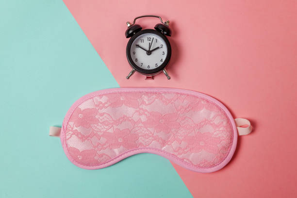 istock Sleeping mask and alarm clock on blue and pink pastel background 1152882692