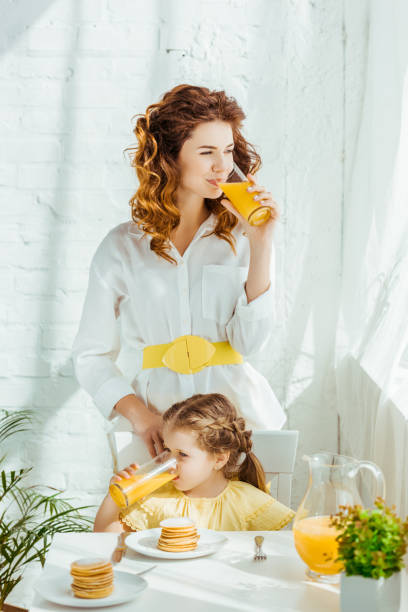 istock mother and daughter drinking orange juice while having breakfast 1152883067