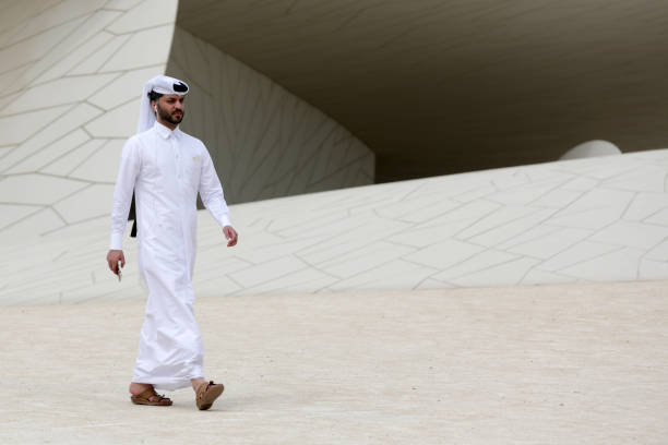 Doha, Qatar - 11 April, 2019: A Qatari man in a long white shirt and a loose headdress walks around The National Museum of Qatar.