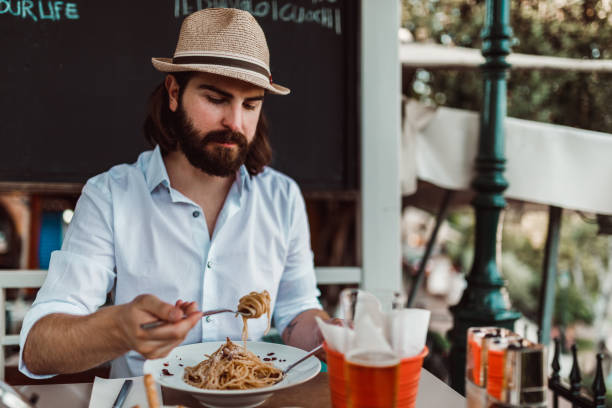 istock Young man eating spaghetti on the restaurant balcony 1152891918