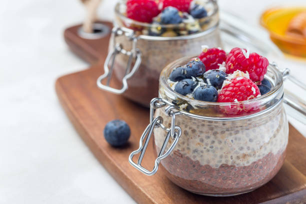istock Layered chocolate and peanut butter chia seed pudding in  jar, garnished with raspberry, blueberry, honey and coconut flakes, horizontal, copy space 1152893232