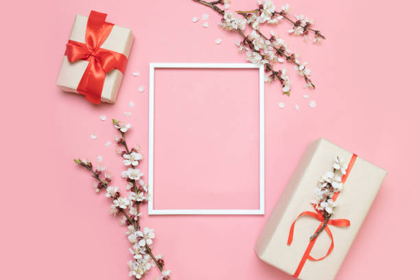 istock White frame, twigs of flowers with gift boxes on a pink background 1152893491