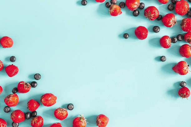 Strawberry and blueberry on blue background. Flat lay, top view