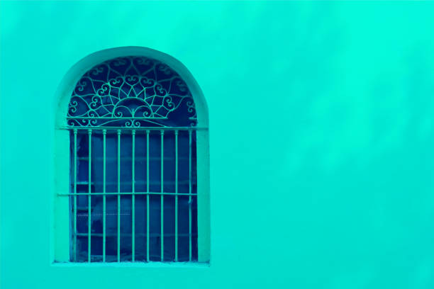 Mint green wrought iron decorated window on mint green concrete wall