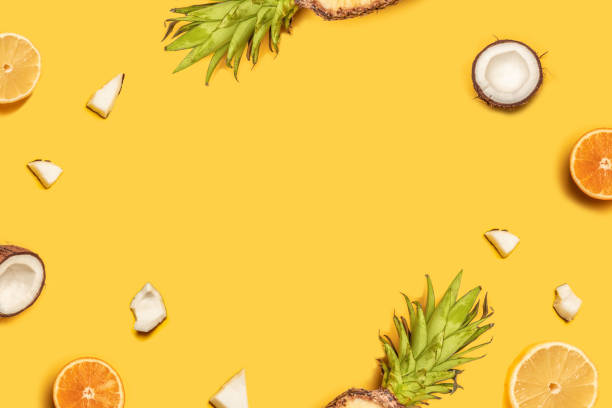 istock Juicy tropical fruits on a yellow background: oranges, coconuts, lemons, pineapples. 1152899259