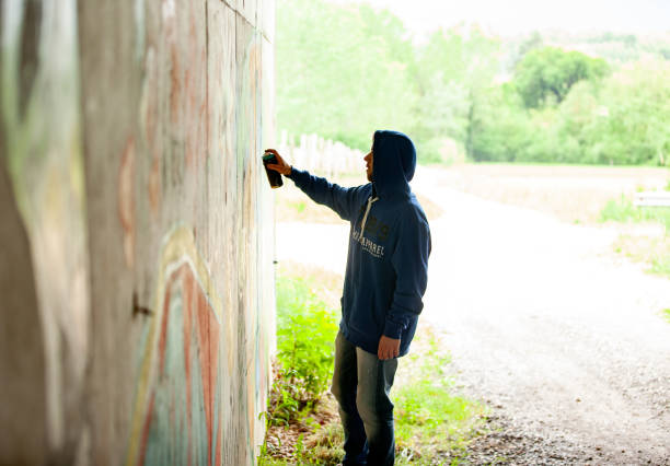 istock Young Adult Man Drawing Graffiti on Wall 1152902832
