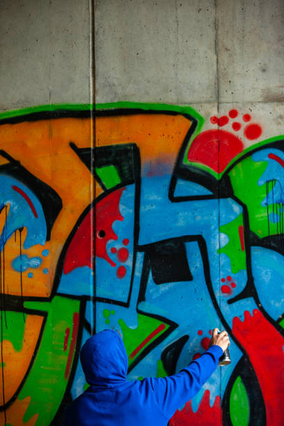 istock Graffiti Artist With Hooded Shirt Drawing Graffiti on Wall 1152902870