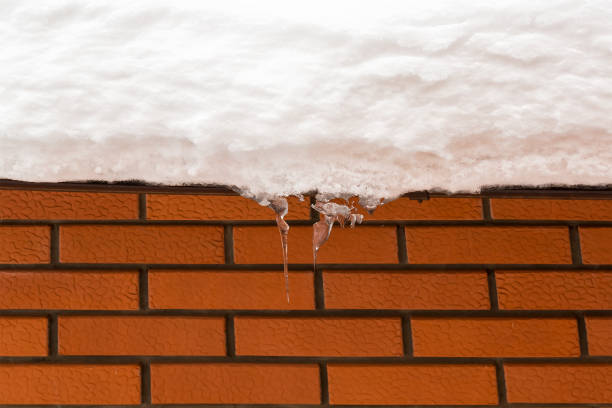 red brick wall. texture. the gutter on the roof of the snow. icicles hanging from snowy roof. danger hangs from the roof. - january winter icicle snowing imagens e fotografias de stock