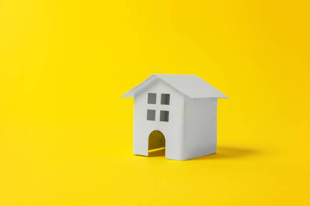 istock Miniature white toy house on yellow background 1152915854