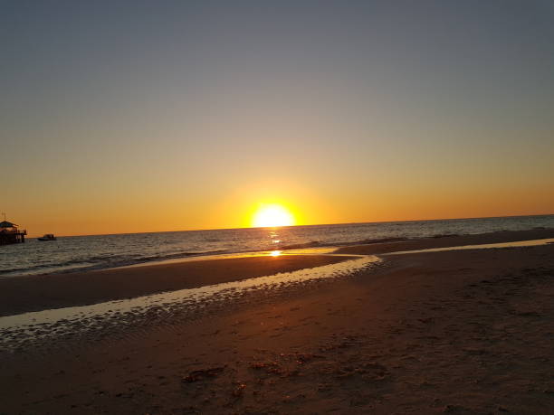 istock Sunset on a beach with Sun's reflection in water 1152915910