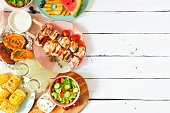 Summer BBQ or picnic food side border, above view over a white wood background