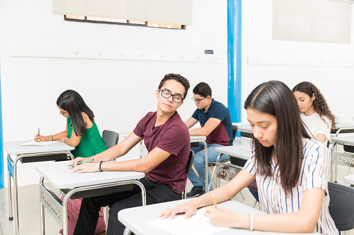 Hispanic boy cheating in admission exam at classroom
