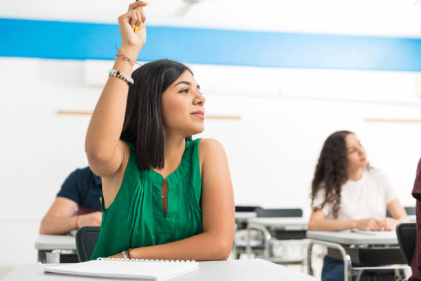 Working Her Way Towards A Distinction Self-assured Latin girl answering in lecture at high school class teenage high school girl raising hand during class stock pictures, royalty-free photos & images