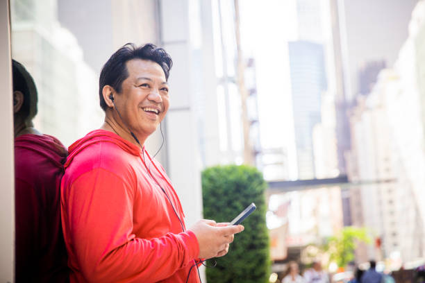 Mature Hispanic Man Using Phone in New York City A mature hispanic man working out in central park in New York City one mature man only audio stock pictures, royalty-free photos & images