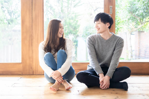 リビングルームでリラックス若いアジアのカップル - women couple men talking ストックフォトと画像