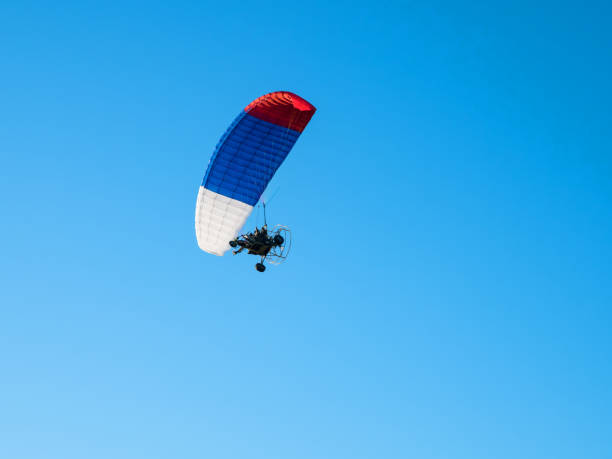 istock Colorful powered paraglider against blue sky. 1152938213