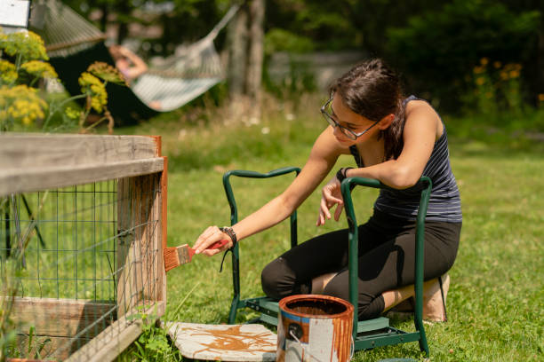 the attractive 15-years-old teenager girl painting the fence at the backyard - teenager 14 15 years 13 14 years cheerful imagens e fotografias de stock