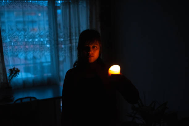Woman with candle at home because of power cut stock photo