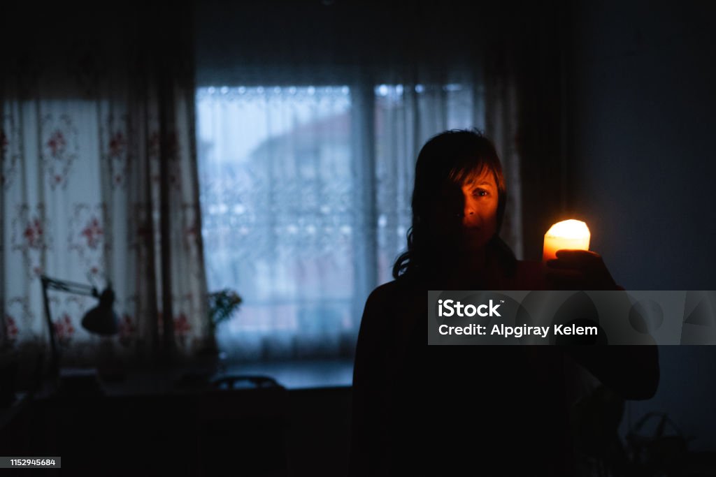 Woman with candle at home because of power cut Blackout Stock Photo