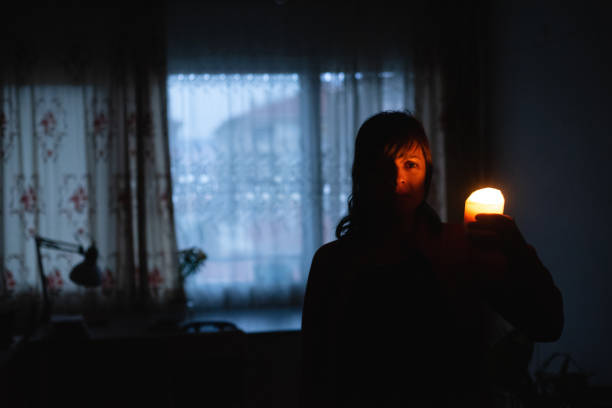 Woman with candle at home because of power cut stock photo