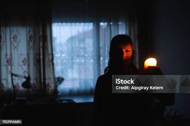 Woman With Candle At Home Because Of Power Cut Stock Photo - Download Image Now - Blackout, Home Interior, Candle