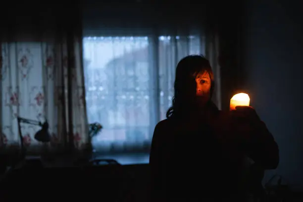 Photo of Woman with candle at home because of power cut