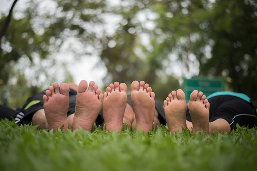 Close up of family feet togetherness on green field.