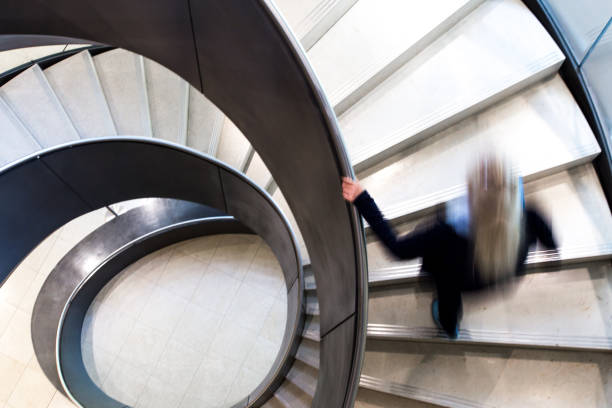istock Blurred Motion of Person on Abstract Spiral Staircase 1152962199