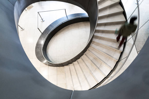 istock Blurred Motion of Person on Abstract Spiral Staircase 1152965672