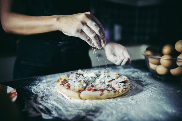 istock Chef hands pouring flour powder on raw dough. Cooking concept. 1152966383