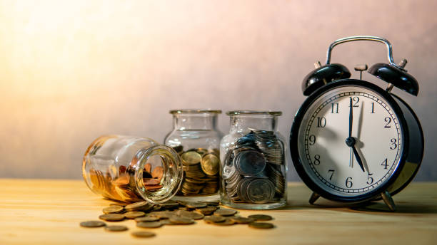 coin jars and clock. saving money for retirement - stock market data insurance savings finance imagens e fotografias de stock