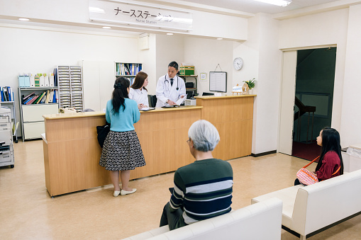 Woman waiting at reception desk for medical appointment, efficiency, organisation, hospital interior