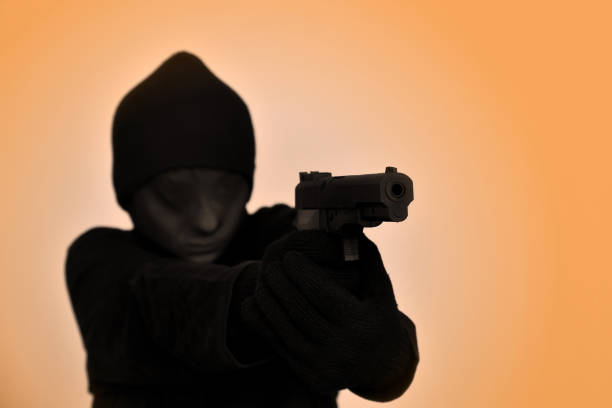 istock Masked female robber holding a gun and aiming 1152982099